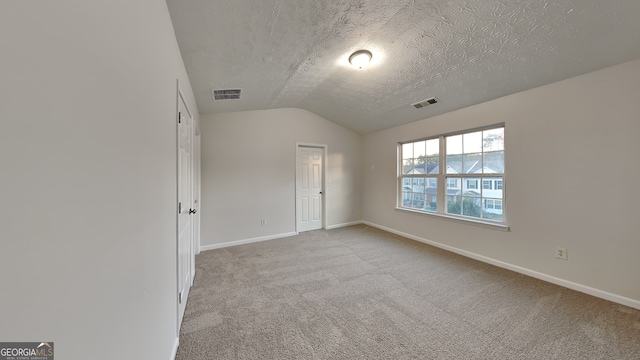 carpeted empty room with a textured ceiling and lofted ceiling