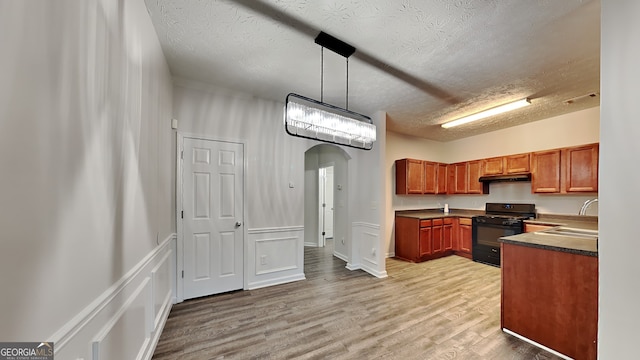 kitchen featuring sink, black range with gas stovetop, light hardwood / wood-style flooring, a textured ceiling, and decorative light fixtures