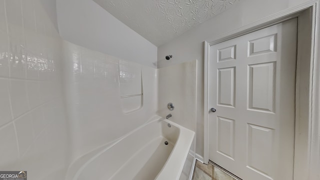 bathroom with bathing tub / shower combination and a textured ceiling