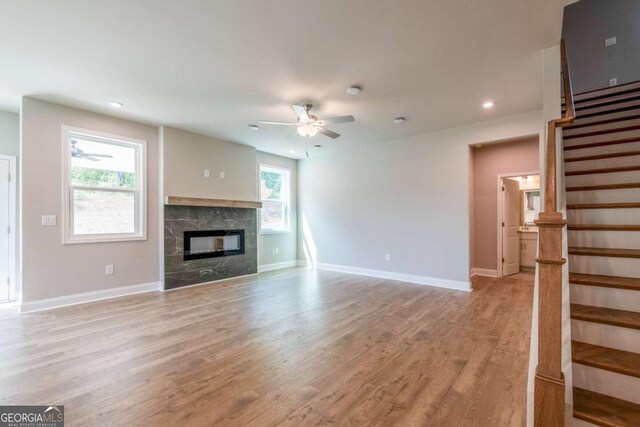 unfurnished living room featuring a fireplace, light hardwood / wood-style floors, and ceiling fan