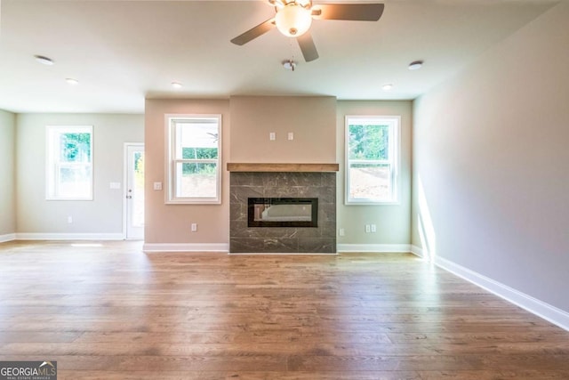 unfurnished living room with hardwood / wood-style flooring, ceiling fan, and a fireplace