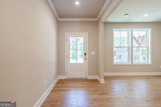 doorway to outside featuring a healthy amount of sunlight, ornamental molding, and light hardwood / wood-style flooring