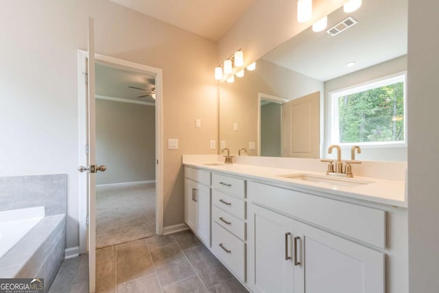 bathroom with tiled tub, ceiling fan, and vanity