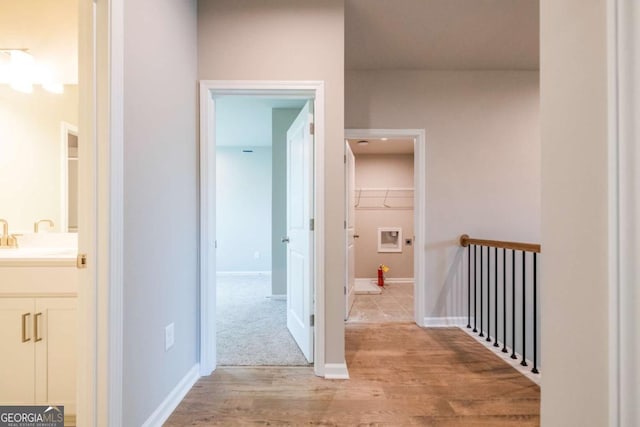 corridor featuring sink and light hardwood / wood-style flooring