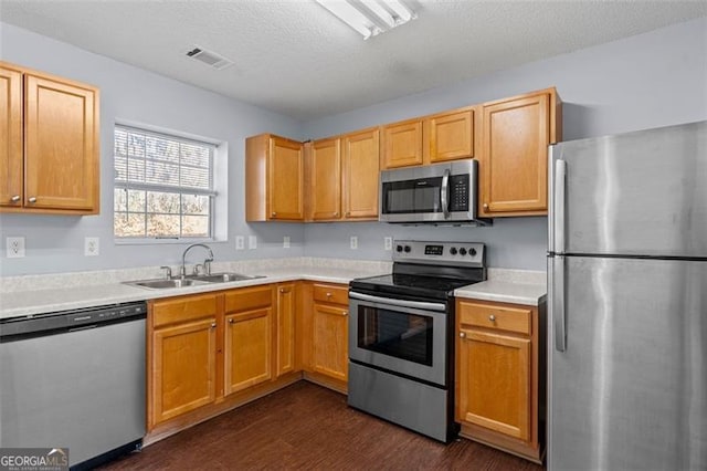 kitchen featuring a textured ceiling, sink, appliances with stainless steel finishes, and dark wood-type flooring