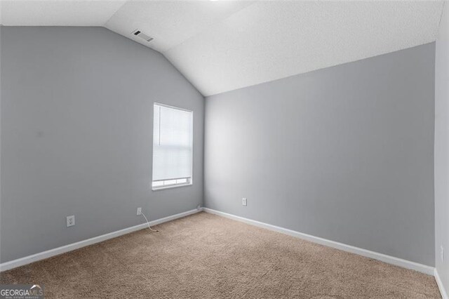 carpeted empty room featuring lofted ceiling