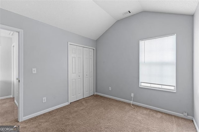 unfurnished bedroom featuring lofted ceiling, light carpet, and a closet