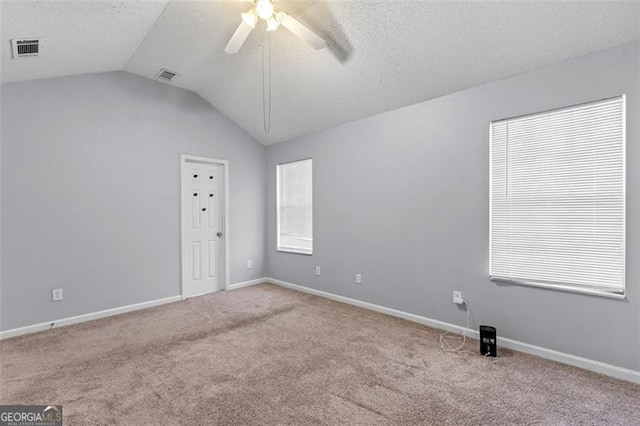 unfurnished room with a textured ceiling, ceiling fan, light colored carpet, and vaulted ceiling