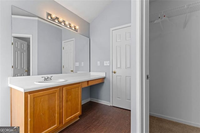 bathroom with hardwood / wood-style floors, vanity, and lofted ceiling