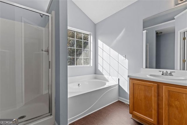 bathroom featuring vanity, independent shower and bath, and vaulted ceiling