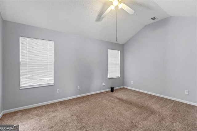 spare room featuring light colored carpet, plenty of natural light, ceiling fan, and lofted ceiling