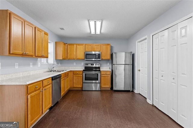 kitchen featuring sink, dark wood-type flooring, a textured ceiling, and appliances with stainless steel finishes