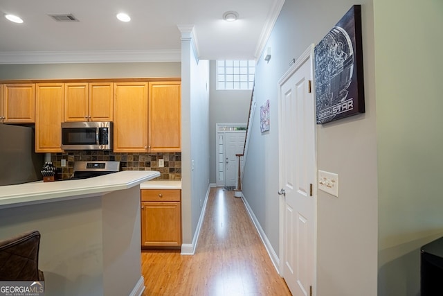 kitchen featuring appliances with stainless steel finishes, tasteful backsplash, crown molding, and light hardwood / wood-style floors