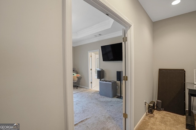 hallway featuring a tray ceiling, light carpet, and ornamental molding