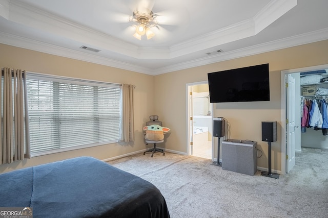 carpeted bedroom featuring a raised ceiling, ceiling fan, ornamental molding, connected bathroom, and a closet