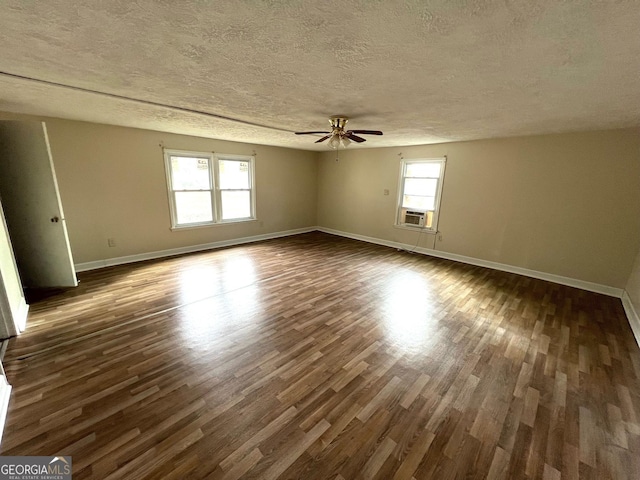 empty room with a textured ceiling, dark hardwood / wood-style flooring, ceiling fan, and cooling unit