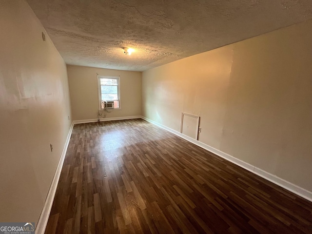 spare room with a textured ceiling, dark hardwood / wood-style floors, and cooling unit