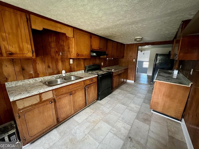 kitchen featuring ceiling fan, sink, black appliances, and wood walls