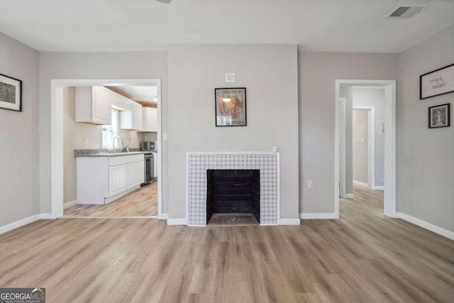 unfurnished living room with light hardwood / wood-style floors and a tile fireplace