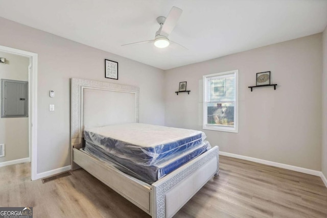 bedroom featuring ceiling fan, light wood-type flooring, and electric panel