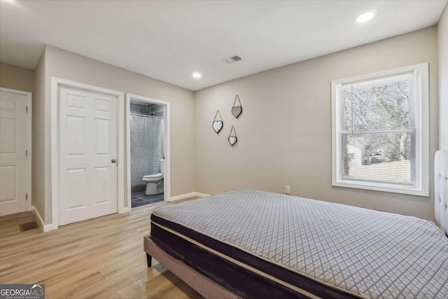 bedroom with light wood-type flooring and ensuite bath