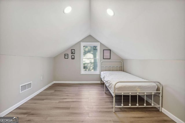 unfurnished bedroom featuring hardwood / wood-style flooring and lofted ceiling