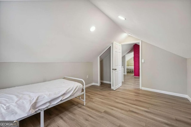 bedroom with light hardwood / wood-style floors and lofted ceiling