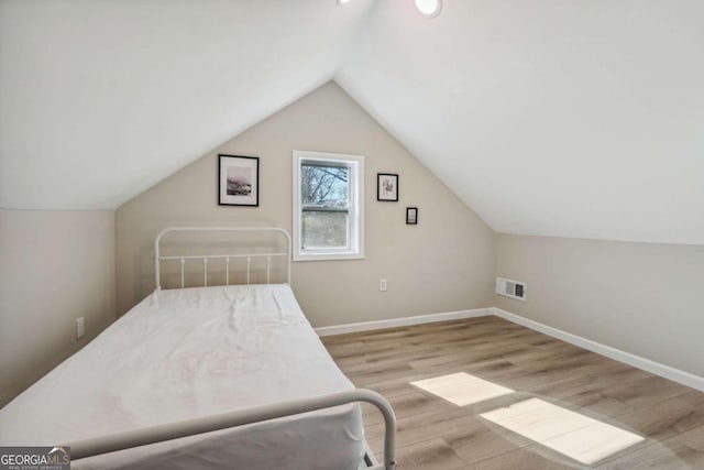 bedroom with light hardwood / wood-style floors and lofted ceiling