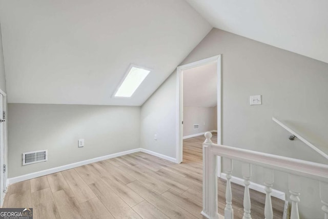 additional living space with light hardwood / wood-style floors and lofted ceiling with skylight