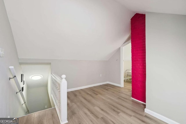 additional living space with light hardwood / wood-style floors and lofted ceiling