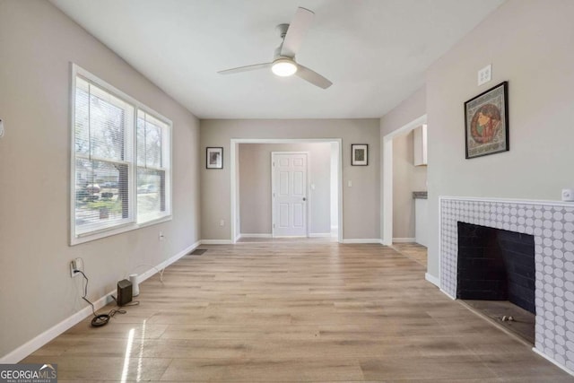 unfurnished living room with a fireplace, light hardwood / wood-style flooring, and ceiling fan