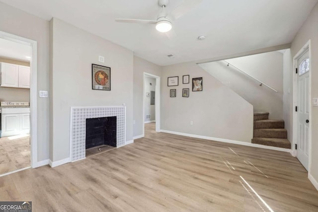 unfurnished living room featuring light hardwood / wood-style floors, ceiling fan, and a tiled fireplace