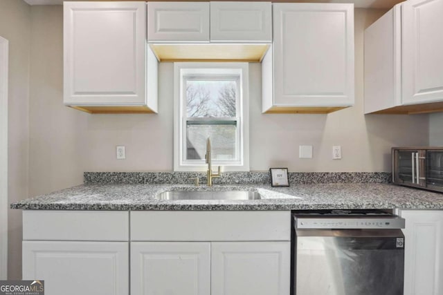 kitchen featuring light stone countertops, white cabinetry, sink, and stainless steel dishwasher