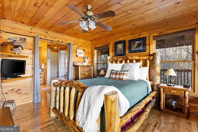 bedroom featuring ceiling fan, hardwood / wood-style flooring, wood ceiling, and wood walls