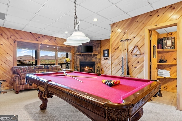 game room featuring light carpet, a paneled ceiling, wooden walls, billiards, and a fireplace