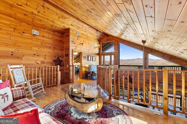 living area with a mountain view, light hardwood / wood-style flooring, wooden walls, and wood ceiling