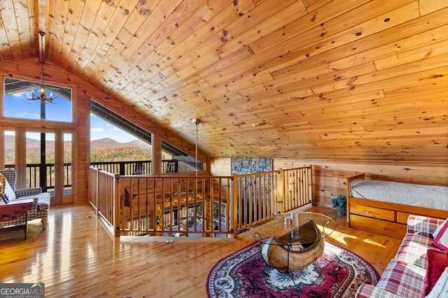 living area with a mountain view, wooden ceiling, wooden walls, light wood-type flooring, and a notable chandelier