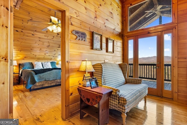 sitting room with ceiling fan, wood walls, a mountain view, and light wood-type flooring