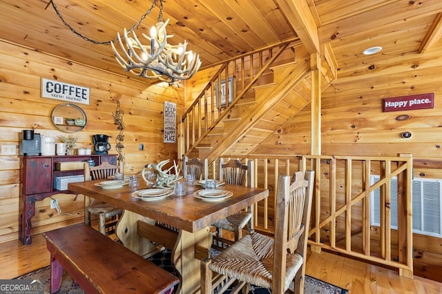 dining space with beam ceiling, wood-type flooring, wooden ceiling, and an inviting chandelier