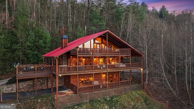 back house at dusk featuring a wooden deck