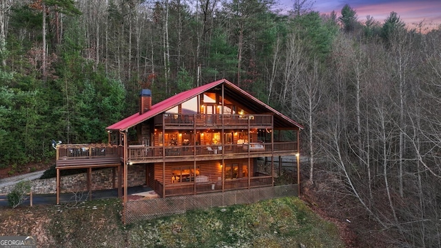 back house at dusk featuring a deck and a patio area