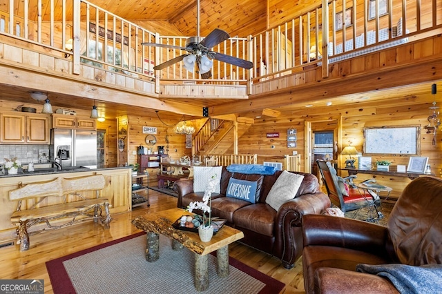 living room with ceiling fan with notable chandelier, hardwood / wood-style flooring, high vaulted ceiling, and wooden ceiling