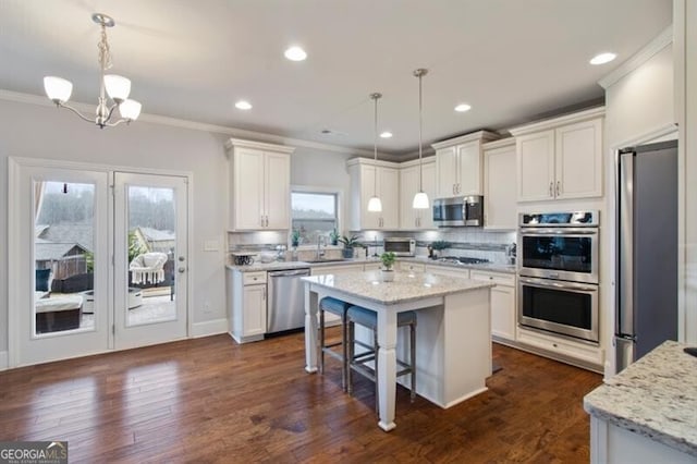 kitchen with stainless steel appliances, a center island, pendant lighting, and white cabinets