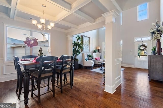 dining room with dark wood-type flooring, coffered ceiling, ornate columns, a notable chandelier, and beam ceiling