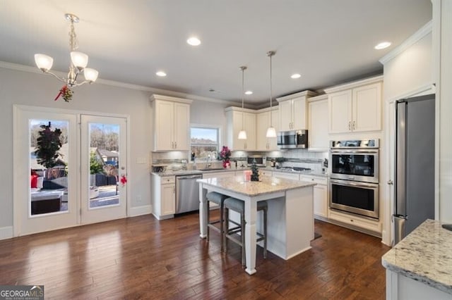 kitchen with light stone counters, decorative light fixtures, stainless steel appliances, and a center island