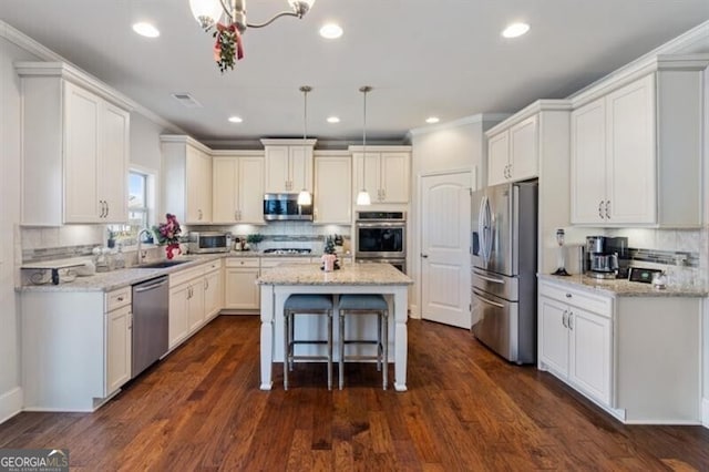 kitchen with pendant lighting, dark wood-type flooring, stainless steel appliances, light stone countertops, and a kitchen island