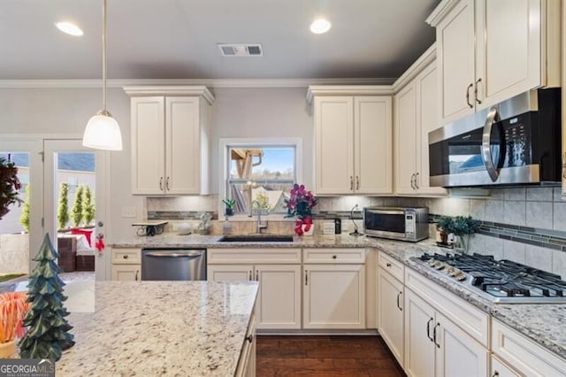 kitchen featuring crown molding, stainless steel appliances, decorative light fixtures, and sink