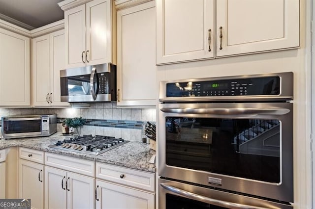 kitchen with stainless steel appliances, tasteful backsplash, and light stone counters