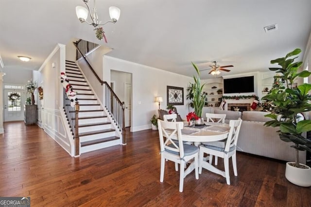 dining area featuring dark hardwood / wood-style flooring, ceiling fan with notable chandelier, and ornamental molding