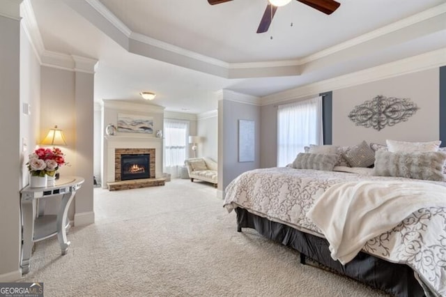 bedroom featuring ceiling fan, carpet flooring, a fireplace, ornamental molding, and a raised ceiling